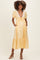 woman wearing a yellow polka dot maternity dress with short puff sleeves, a tie front, and pockets