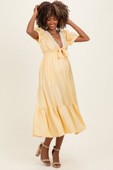 woman wearing a yellow polka dot maternity dress with a tie waist and flutter sleeves, showcasing her baby bump