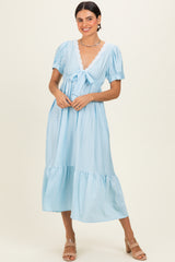 woman wearing a light blue polka dot midi dress with short puff sleeves and a tie-front detail