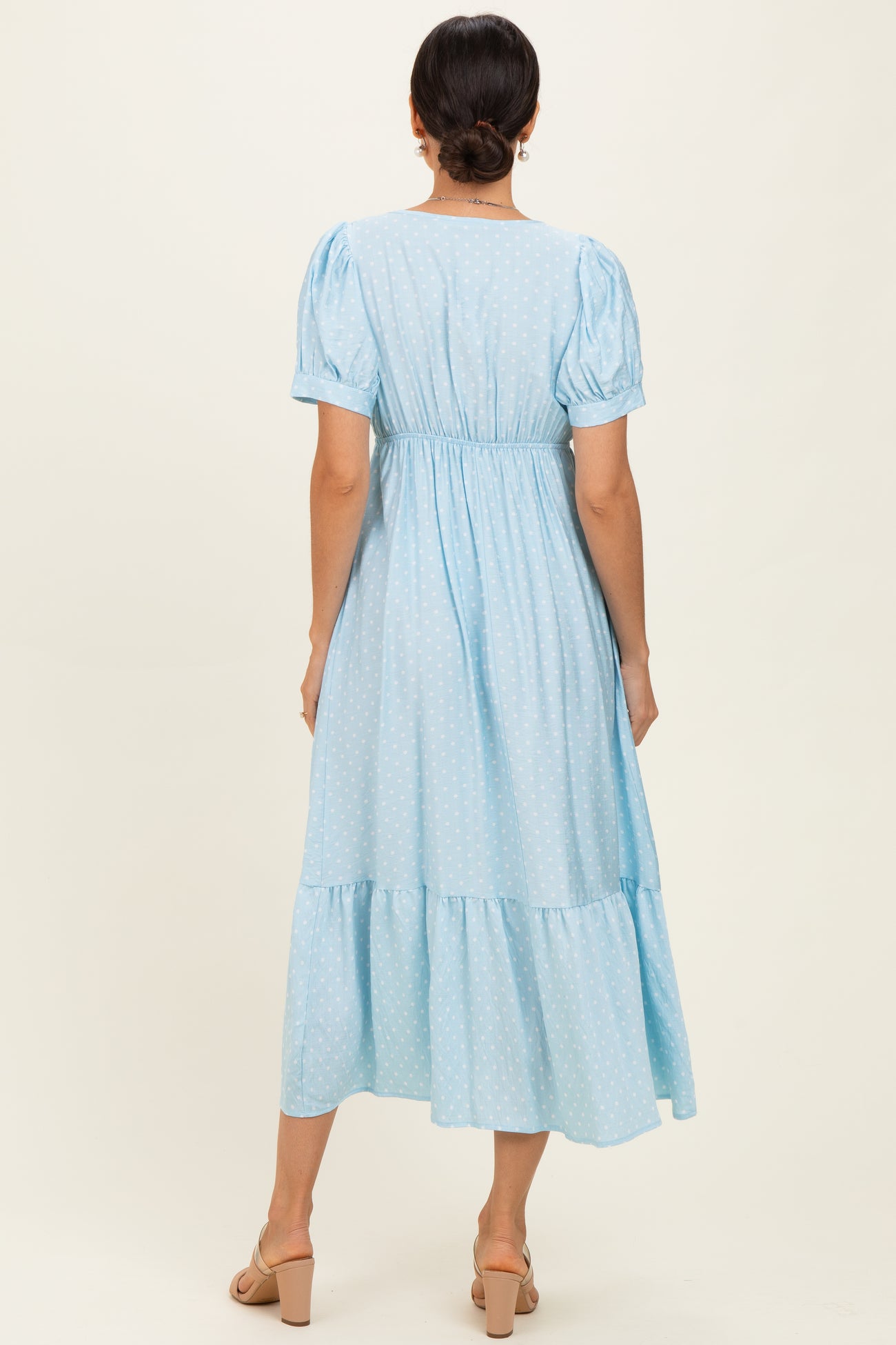 woman wearing a light blue polka dot midi dress with puff sleeves and a tiered skirt