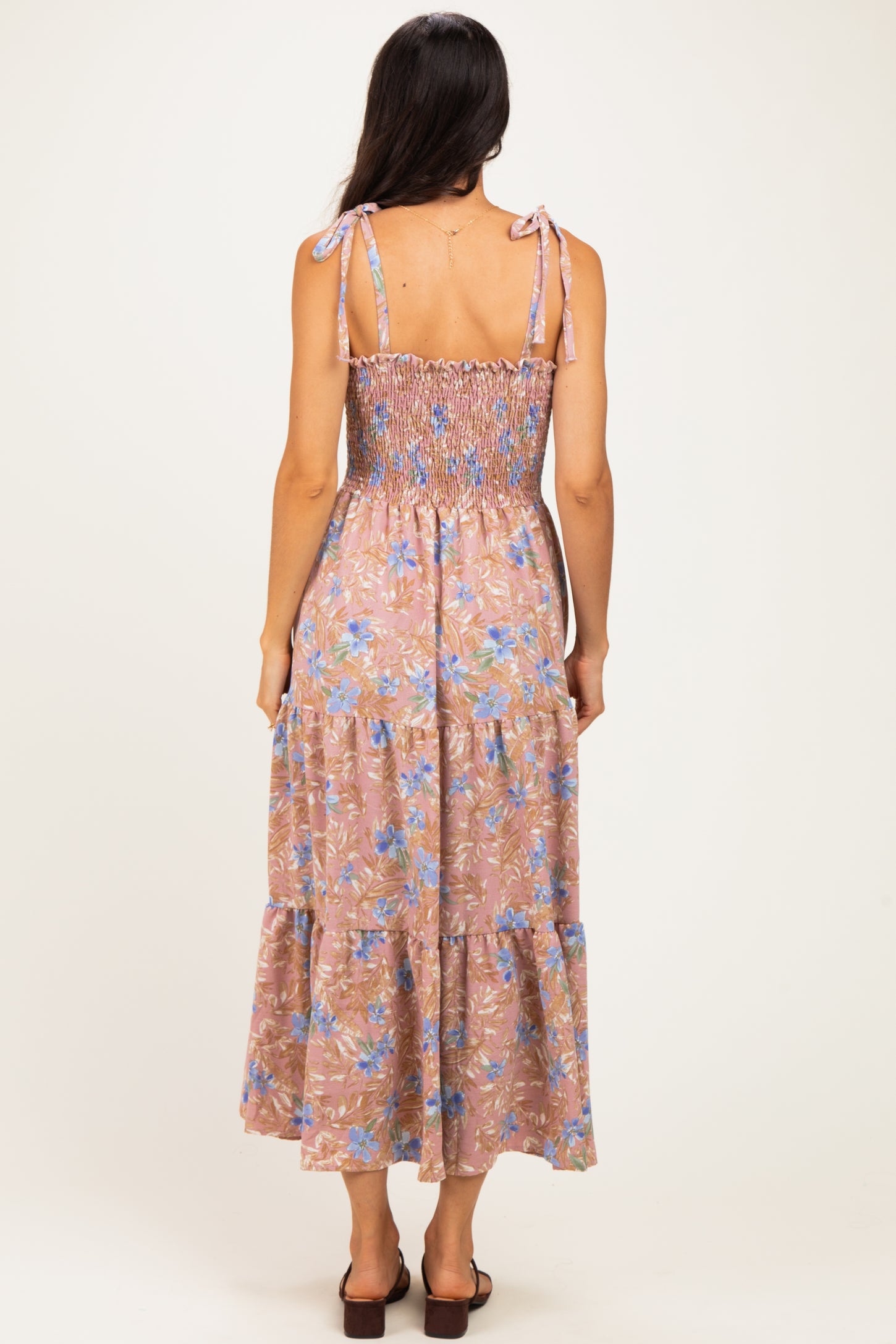 woman wearing a back view of a floral maxi dress with adjustable tie straps and a smocked bodice