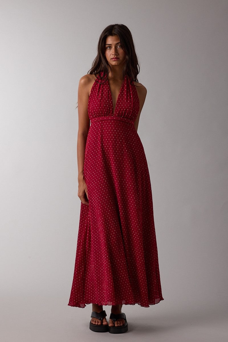 woman wearing a red polka dot halter maxi dress with a flowing skirt and black slide sandals