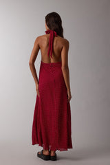 woman wearing a red polka dot backless maxi dress with a halter neck and a flowing skirt