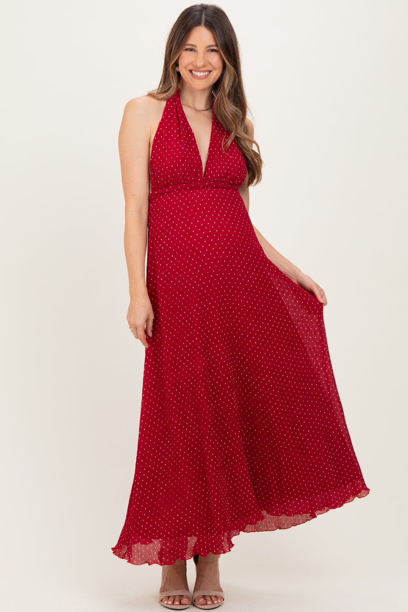 woman wearing a red polka dot maternity maxi dress with a halter neckline and flowing hemline