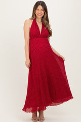 woman wearing a red polka dot maternity maxi dress with a halter neckline and flowing hemline
