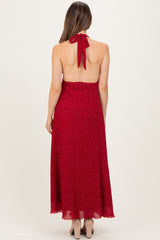 woman wearing a red polka dot maternity maxi dress with a halter neck and open back design