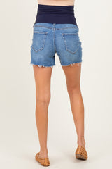woman wearing maternity denim shorts with a distressed hem and a stretchy navy waistband, showing her bare skin and legs