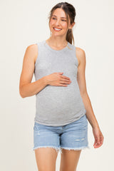woman wearing a gray sleeveless maternity tank top and denim shorts, holding her baby bump