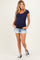 woman wearing a navy blue short sleeve maternity top and denim shorts, showing her baby bump