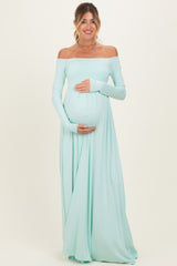 woman wearing a light mint off-shoulder maternity gown and holding her baby bump