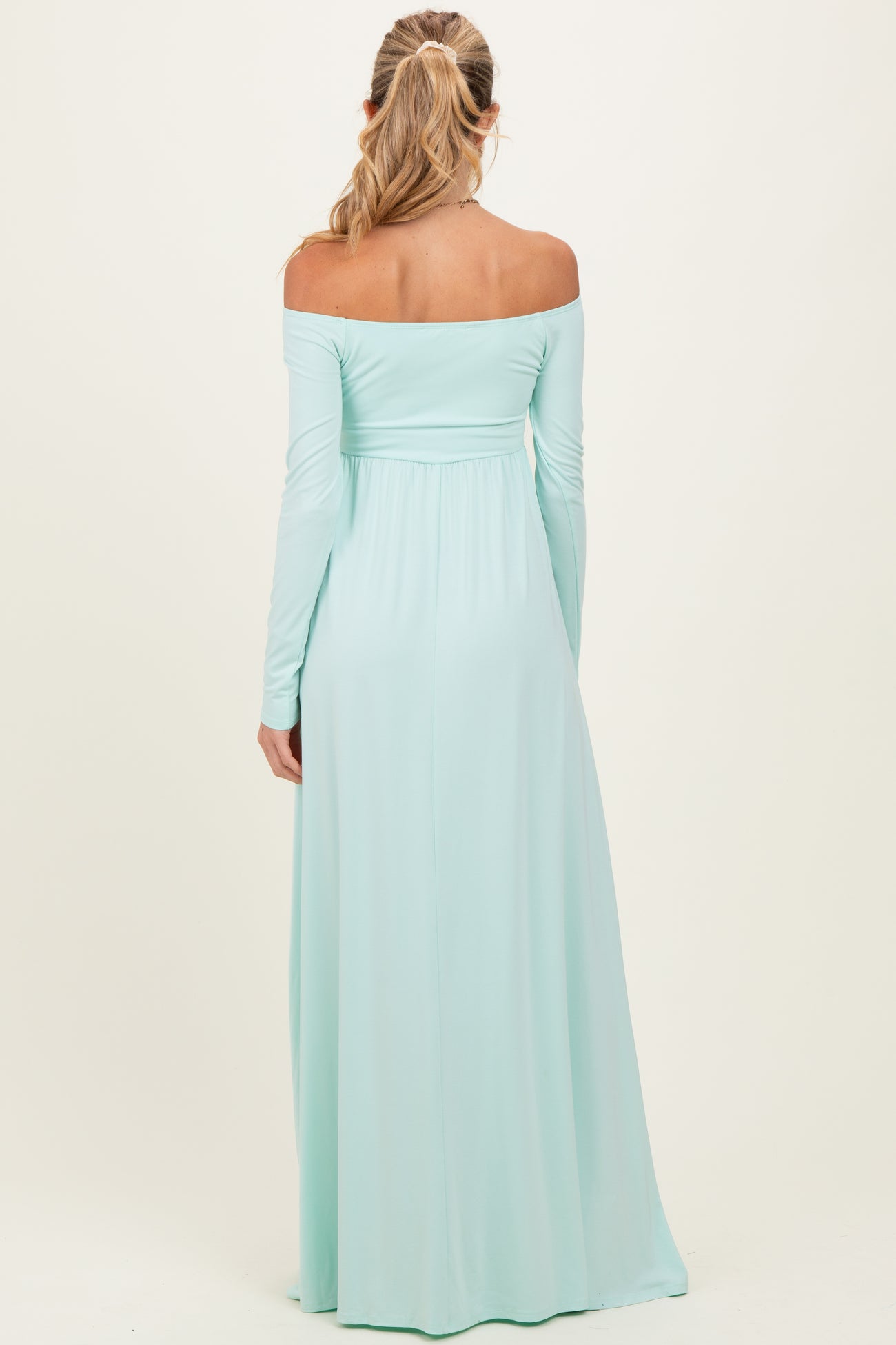woman wearing a mint green off-the-shoulder maternity maxi dress from the back