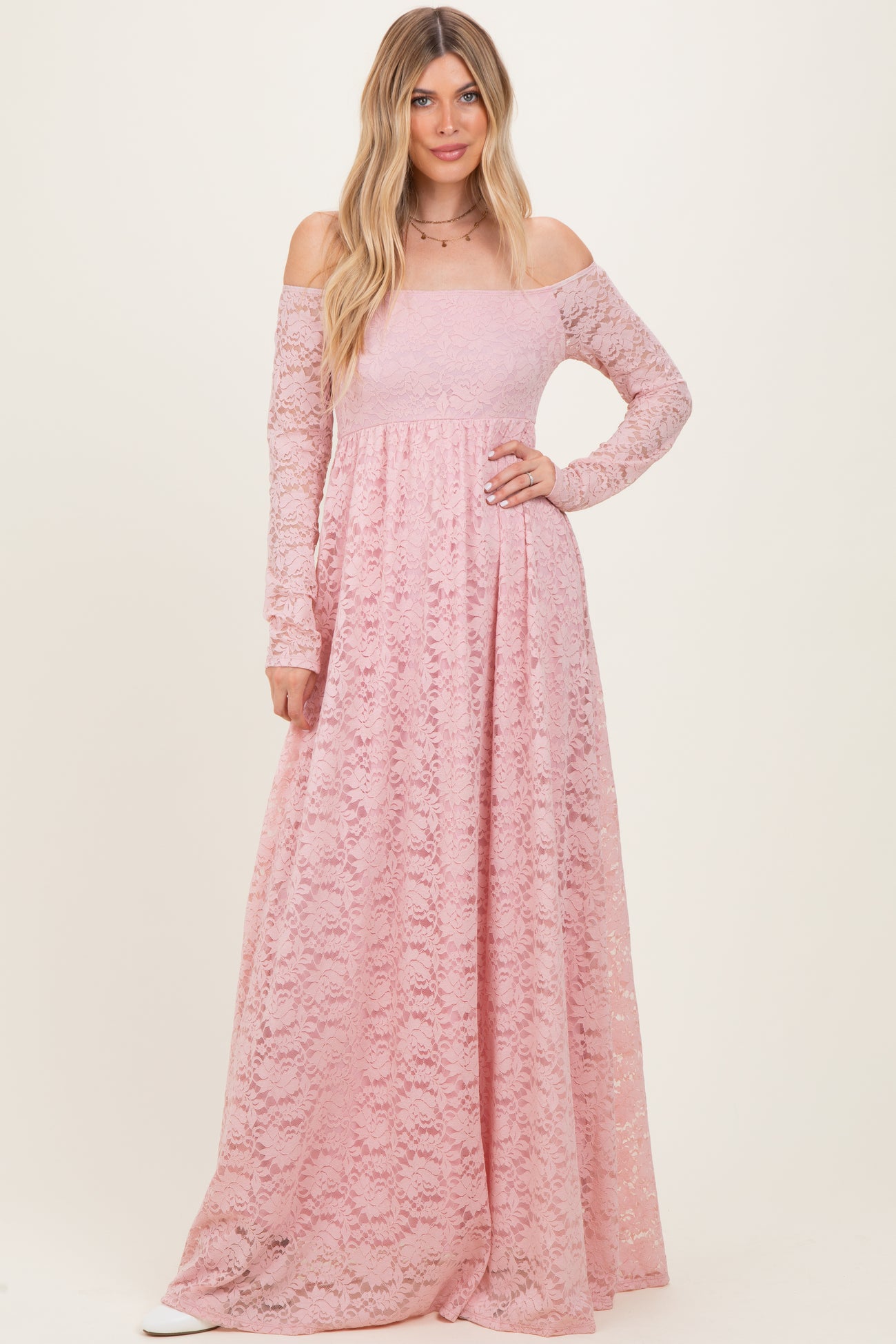 woman wearing a long pink off-the-shoulder lace maxi dress with long sleeves and a flowing skirt