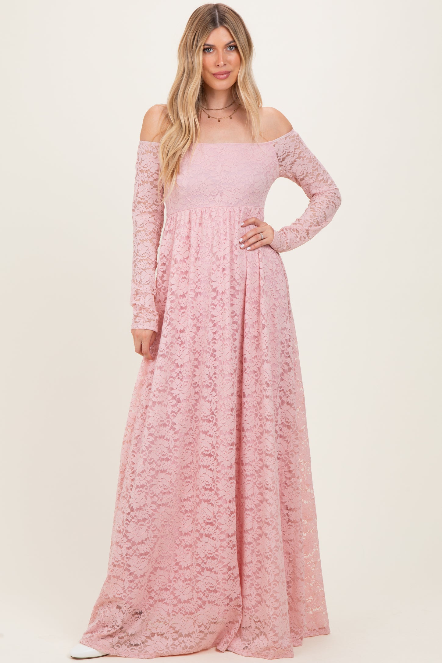 woman wearing a long pink off-the-shoulder lace maxi dress with long sleeves and a flowing skirt