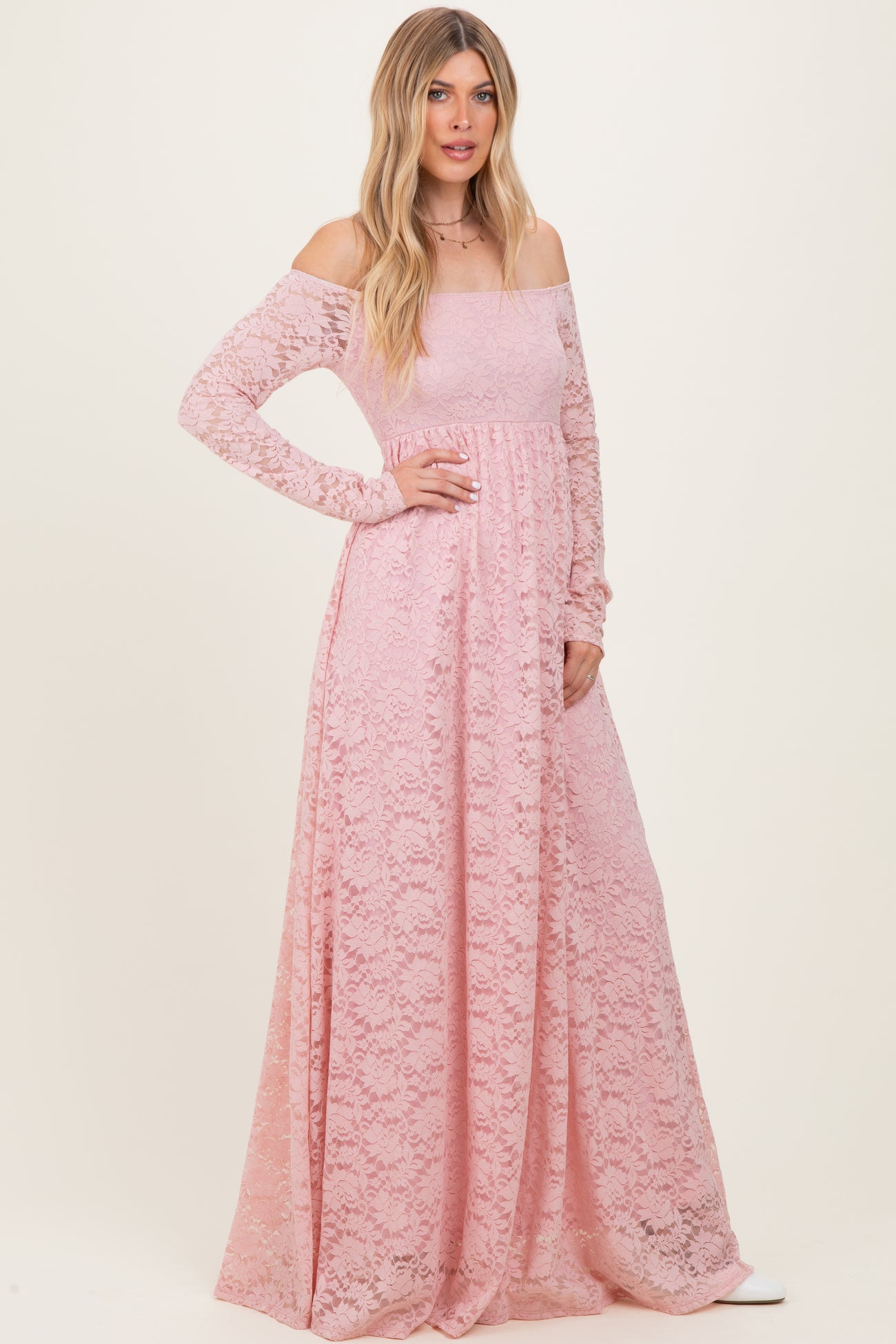 woman wearing a long pink lace off-shoulder maxi dress with long sleeves and a fitted bodice