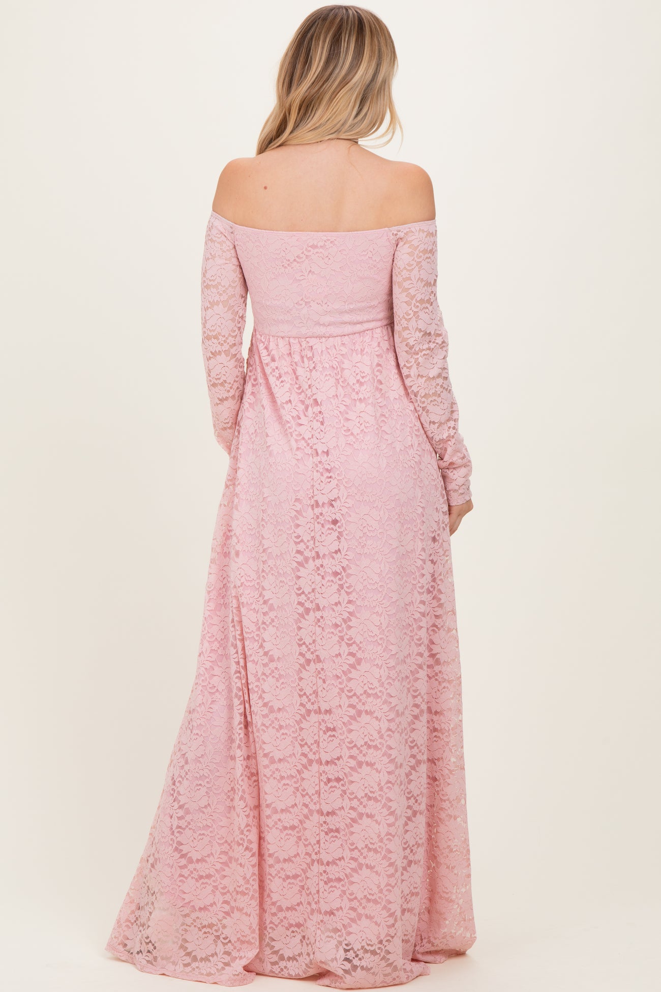 woman wearing a blush pink off-the-shoulder lace maxi dress with long sleeves, seen from the back