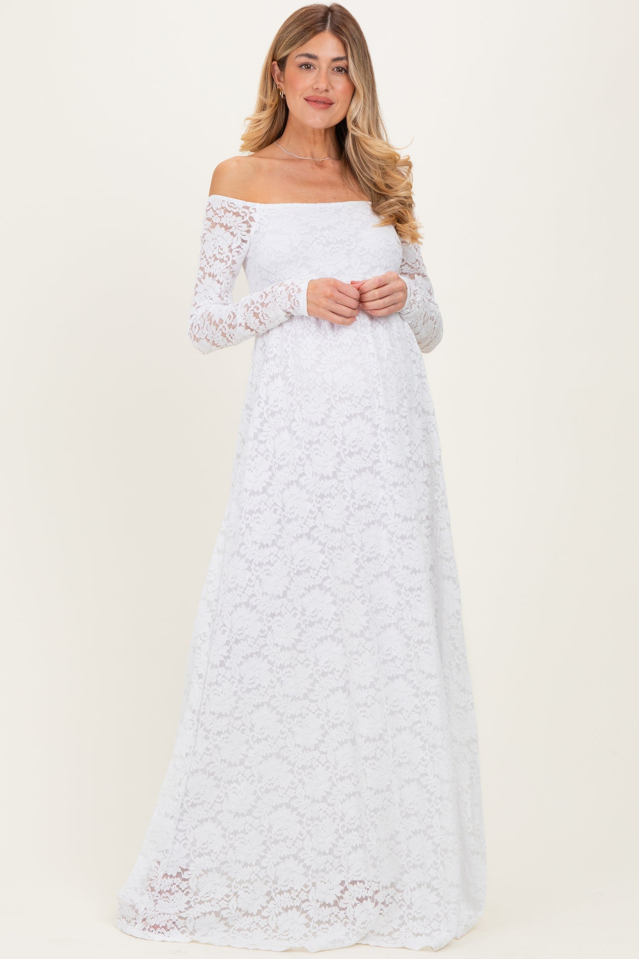 woman wearing a white off-the-shoulder long sleeve lace maternity dress with a flowing skirt and a relaxed fit