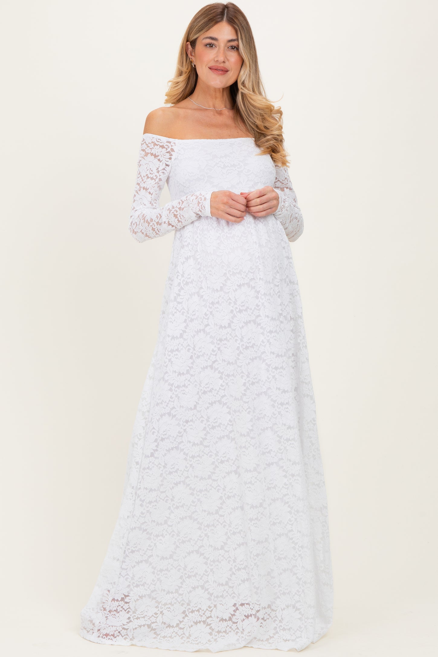 woman wearing a white off-the-shoulder long sleeve lace maternity dress with a flowing skirt and a relaxed fit
