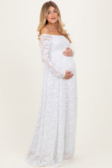 woman wearing a white lace off-shoulder maternity dress and holding her baby bump