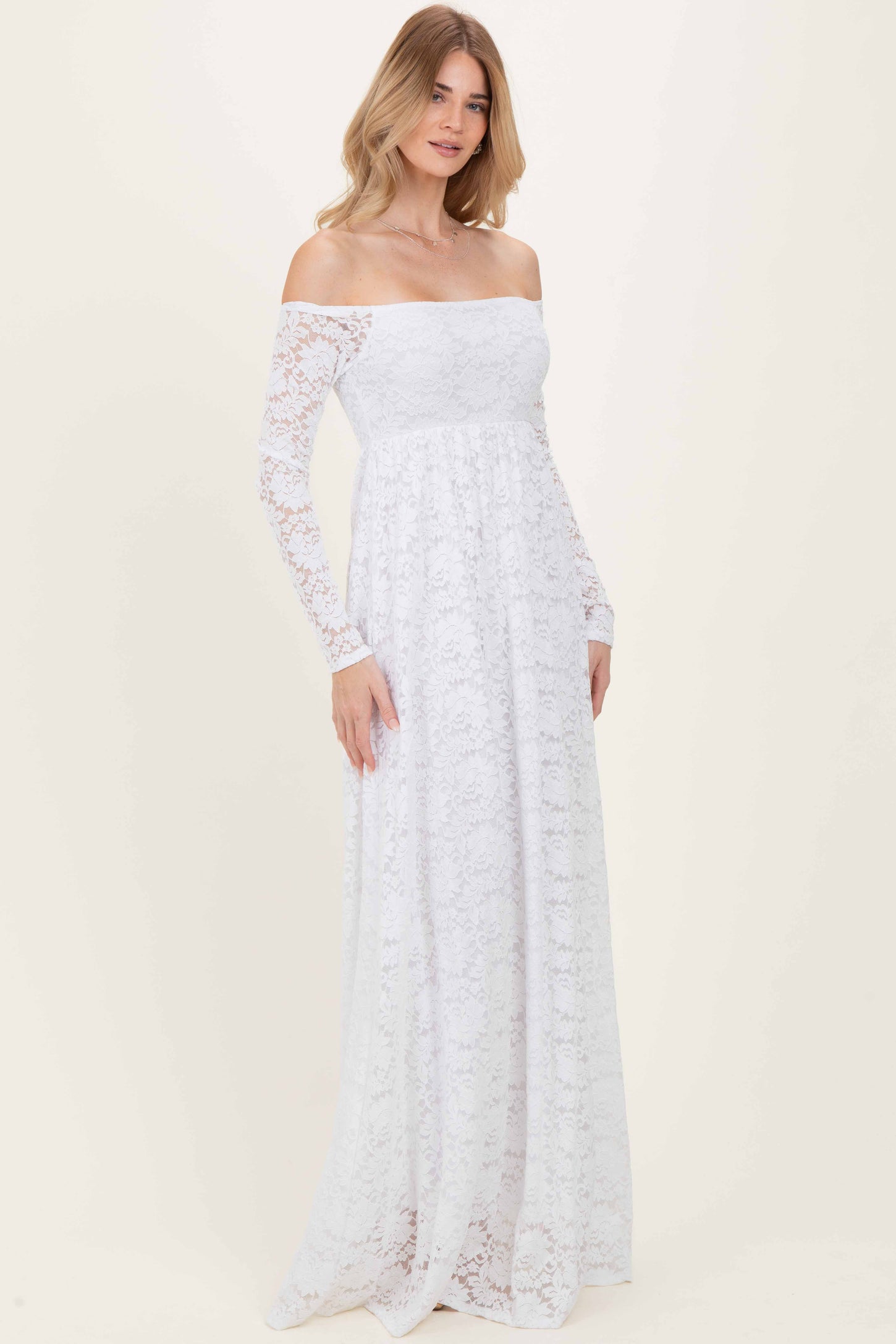 woman wearing a white off-the-shoulder lace maxi dress with long sleeves and a flowy skirt