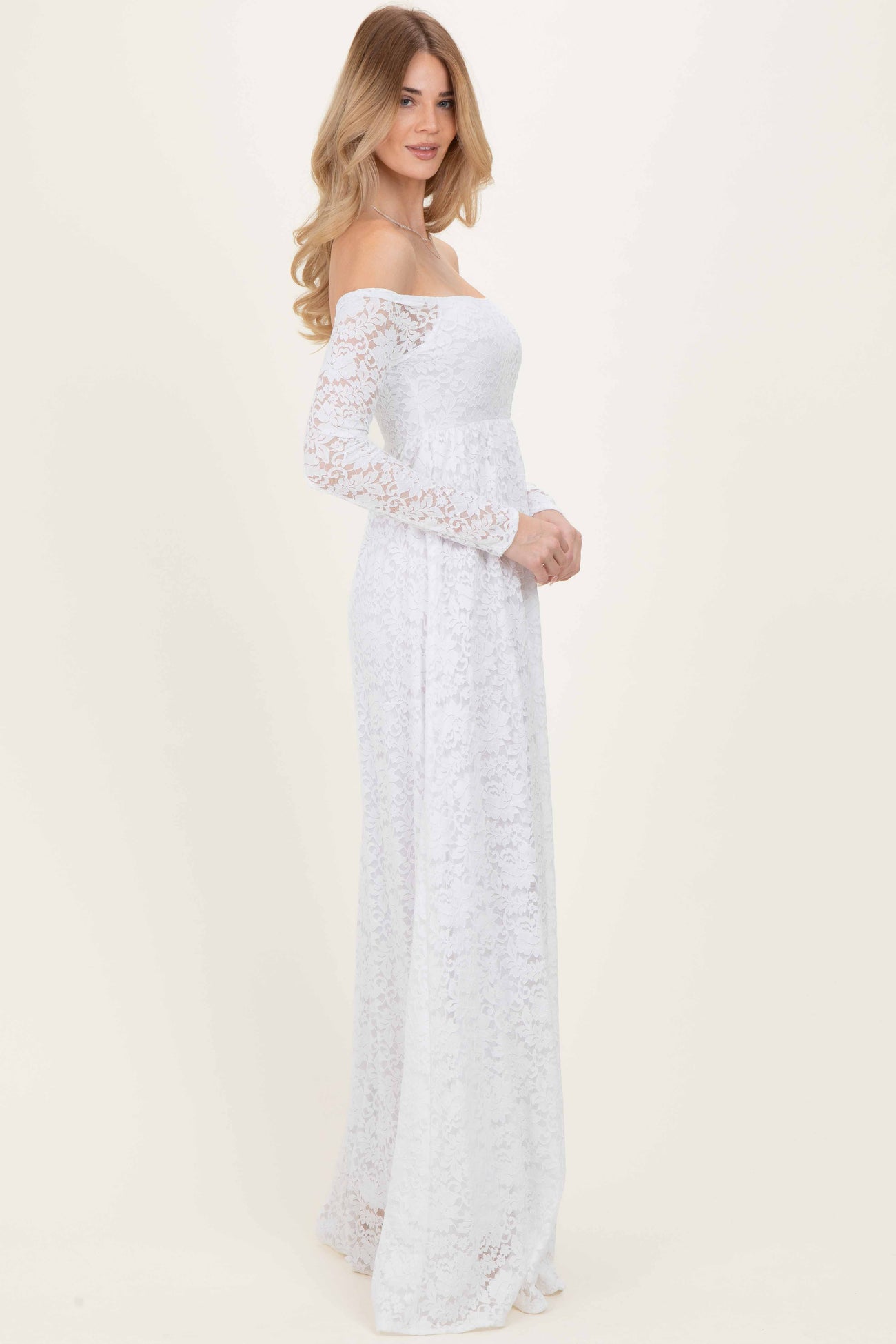 woman wearing a white off-the-shoulder lace maxi dress with long sleeves