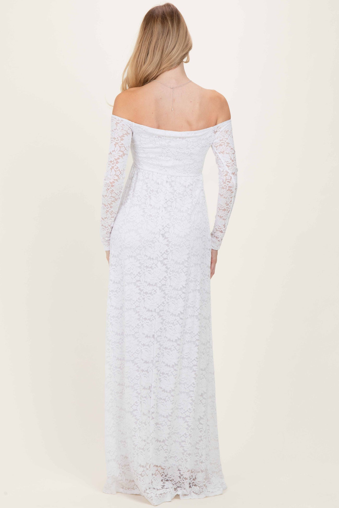 woman wearing a white off-shoulder lace maxi dress with long sleeves, seen from the back