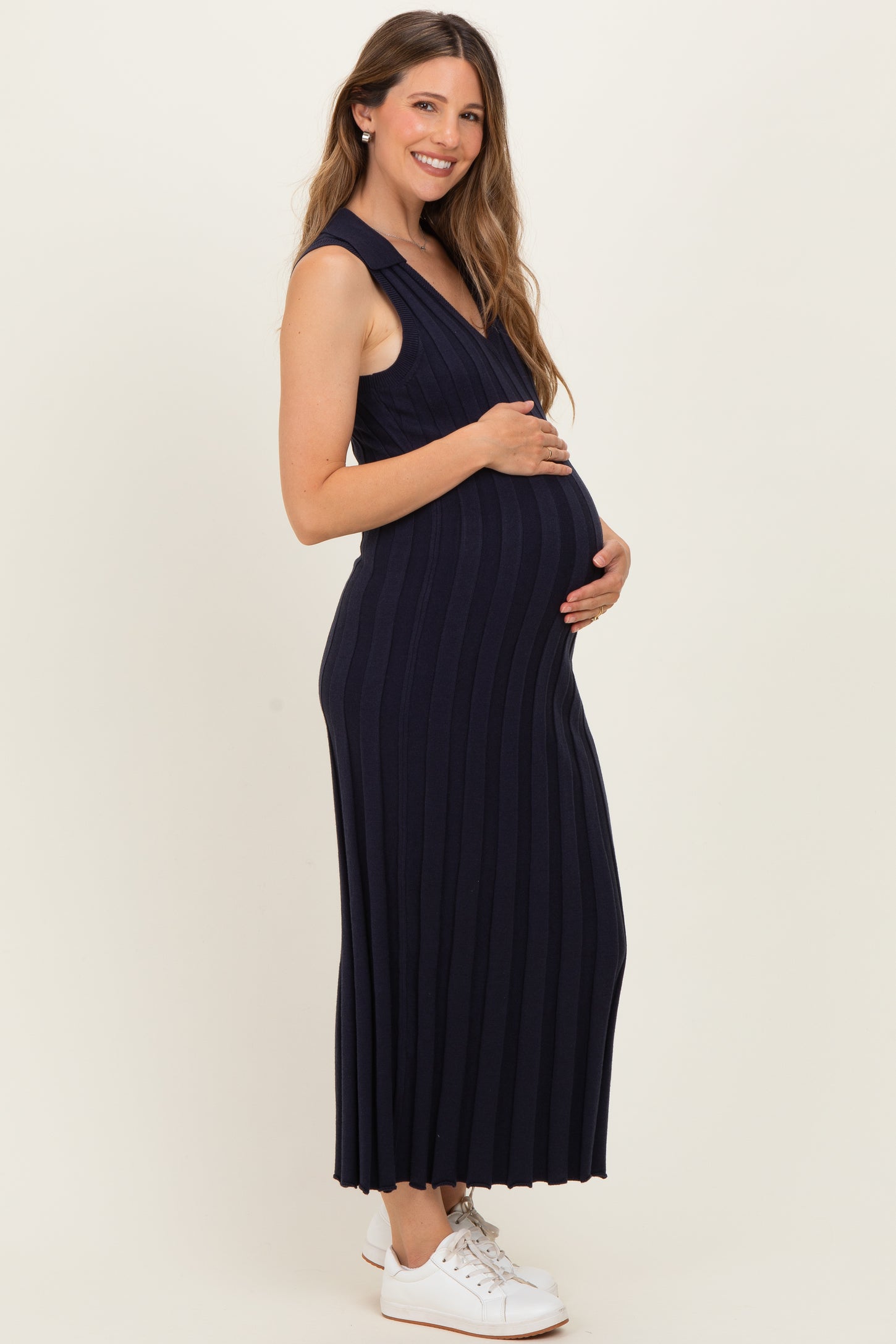 woman wearing a navy blue ribbed maternity dress and holding her baby bump