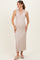 woman wearing a light beige maternity dress with a v-neck and vertical stripes, holding her baby bump