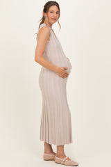 woman wearing a light beige ribbed maternity dress and cradling her baby bump