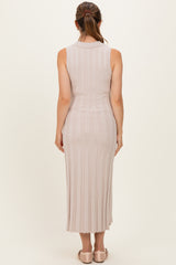 woman wearing a fitted light pink ribbed maternity dress with a midi length and sleeveless design, showing her back