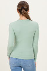 woman wearing a light green long sleeve maternity top viewed from the back with jeans