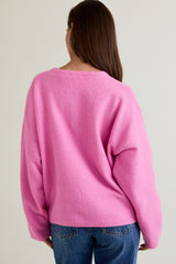 woman wearing a pink oversized sweater with a relaxed fit and back view, paired with blue jeans