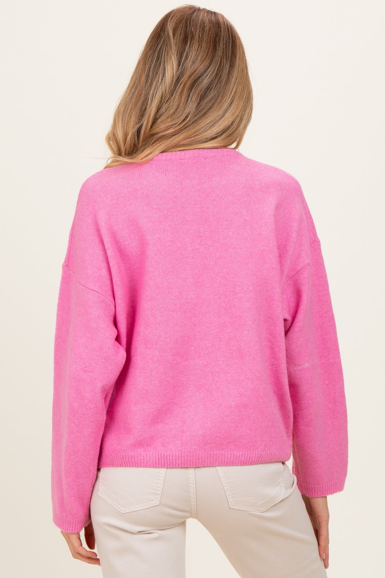 woman wearing a bright pink oversized maternity sweater, shown from the back