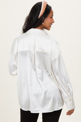 woman wearing a maternity white satin button-up shirt, showing the back view with long sleeves and a relaxed fit