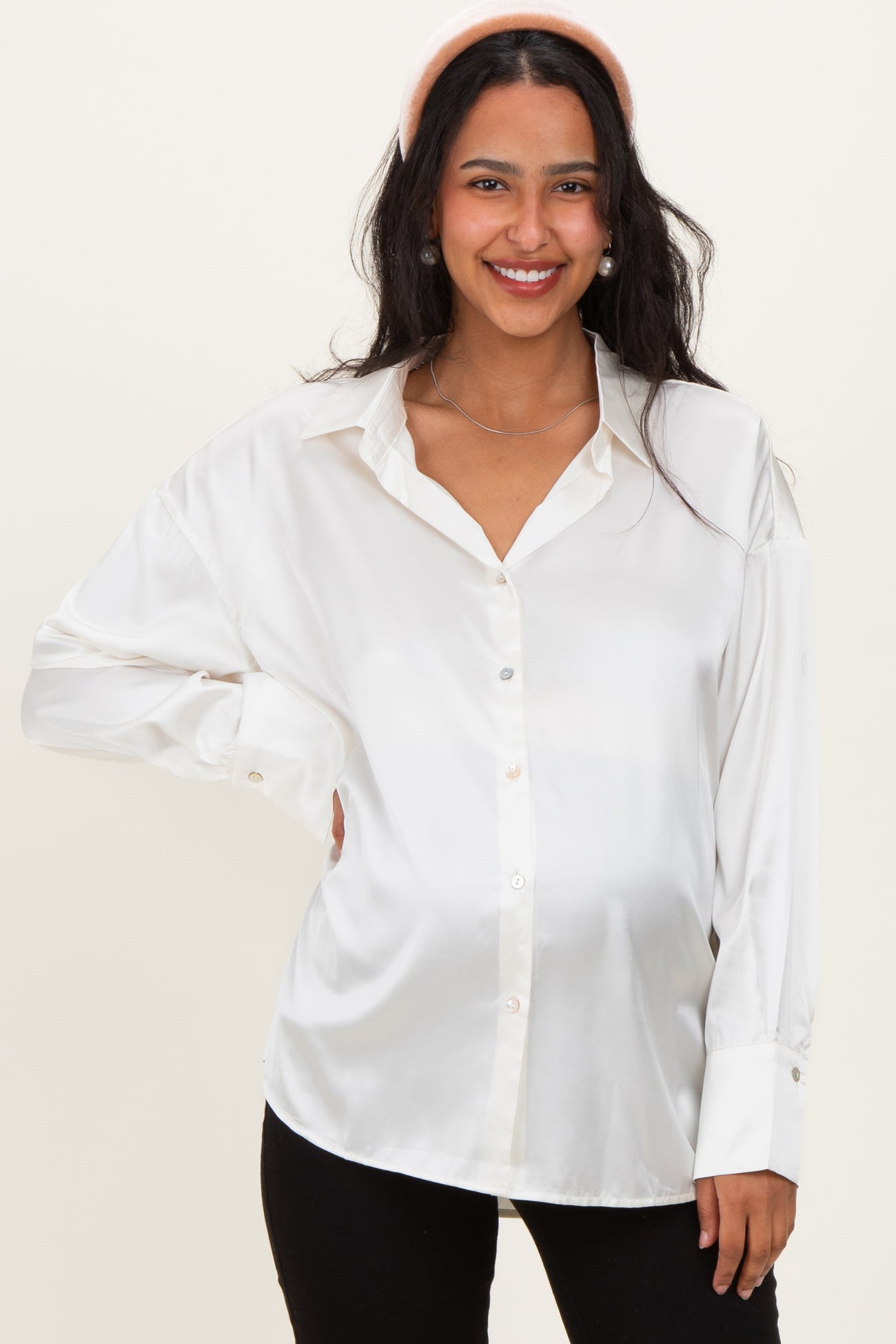 woman wearing a maternity shiny white button-up shirt and black leggings, showing her baby bump