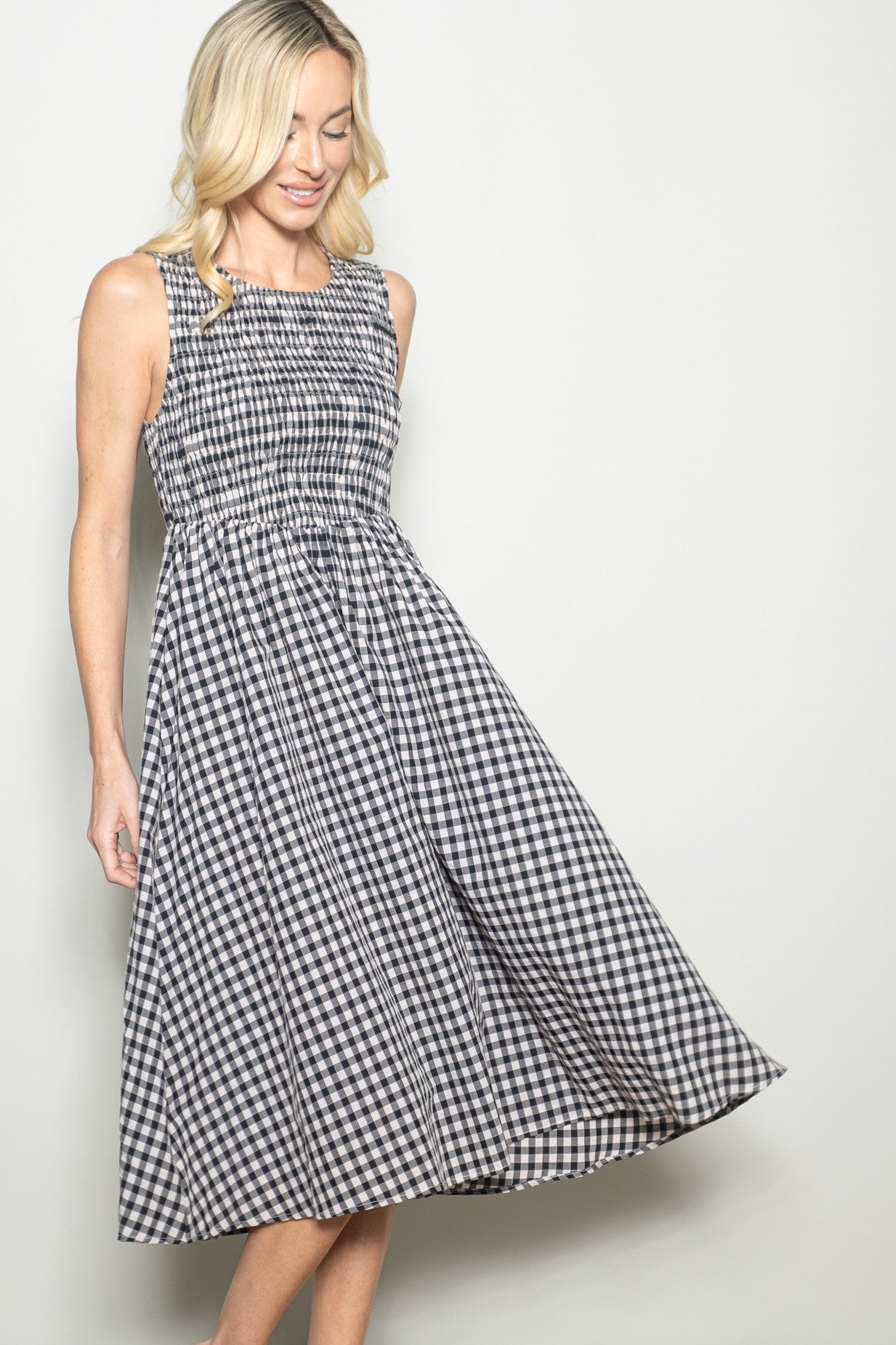 woman wearing a black and white gingham sleeveless midi dress with a smocked bodice and flowing skirt