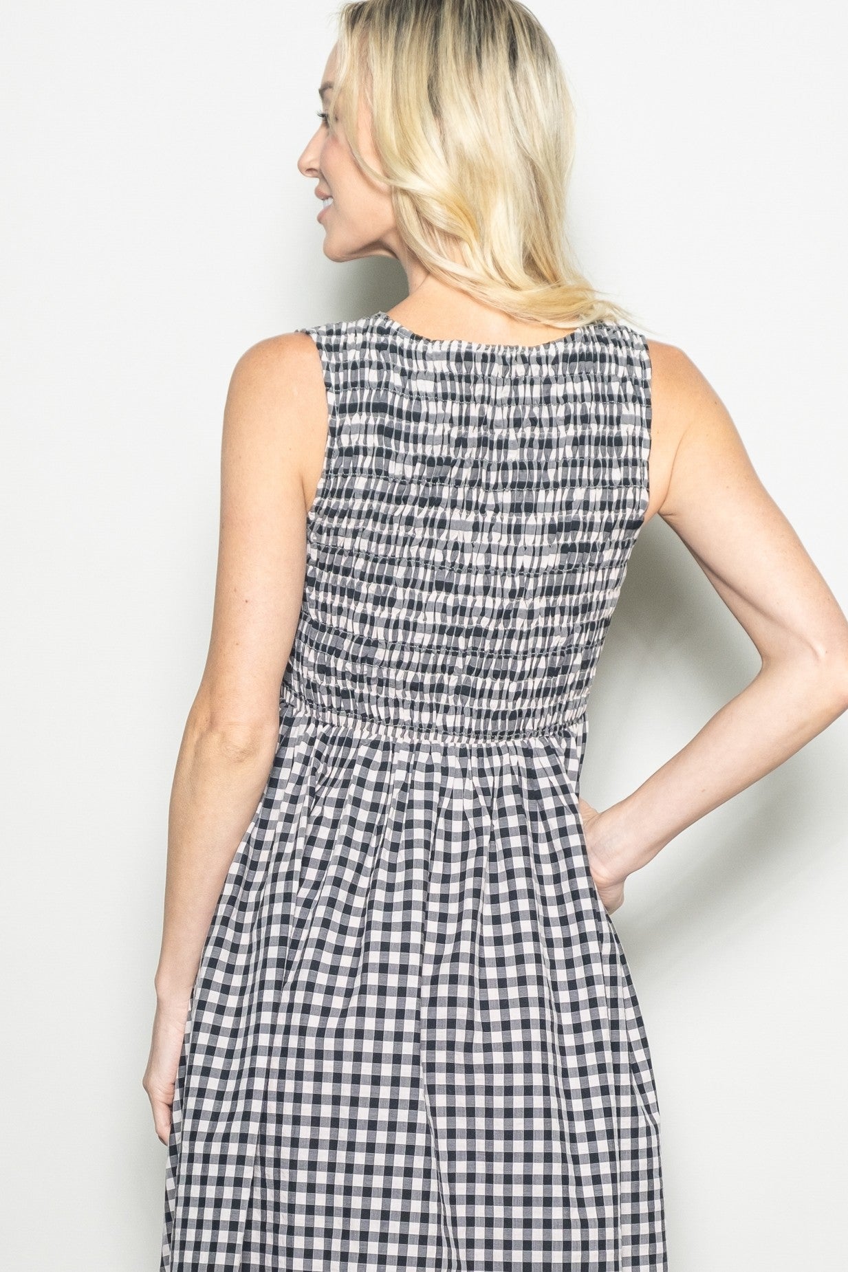 woman wearing a black and white gingham dress with a smocked back and sleeveless design