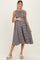woman wearing a black and white gingham sleeveless maternity dress and holding her baby bump