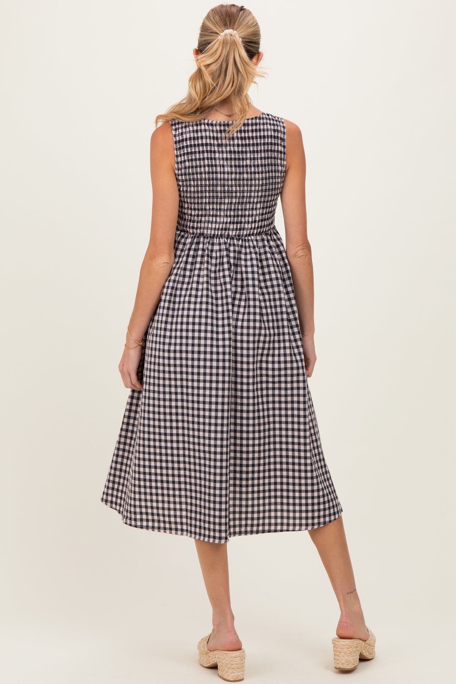 woman wearing a black and white gingham midi maternity dress, showing a fitted bodice and flowy skirt