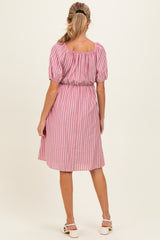 woman wearing a pink and white striped maternity dress with puff sleeves and a gathered waist, seen from the back