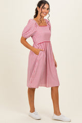 woman wearing a pink and white striped short sleeve dress with a square neckline and pockets