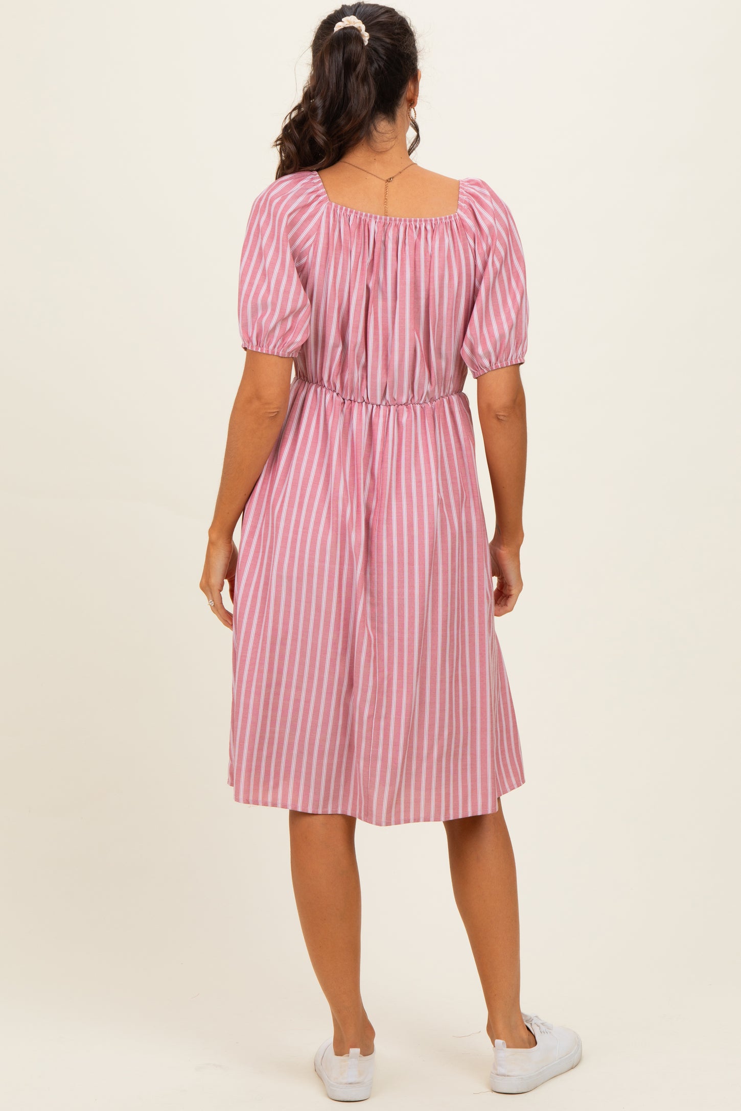 woman wearing a pink and white striped short sleeve dress with a cinched waist and a midi length