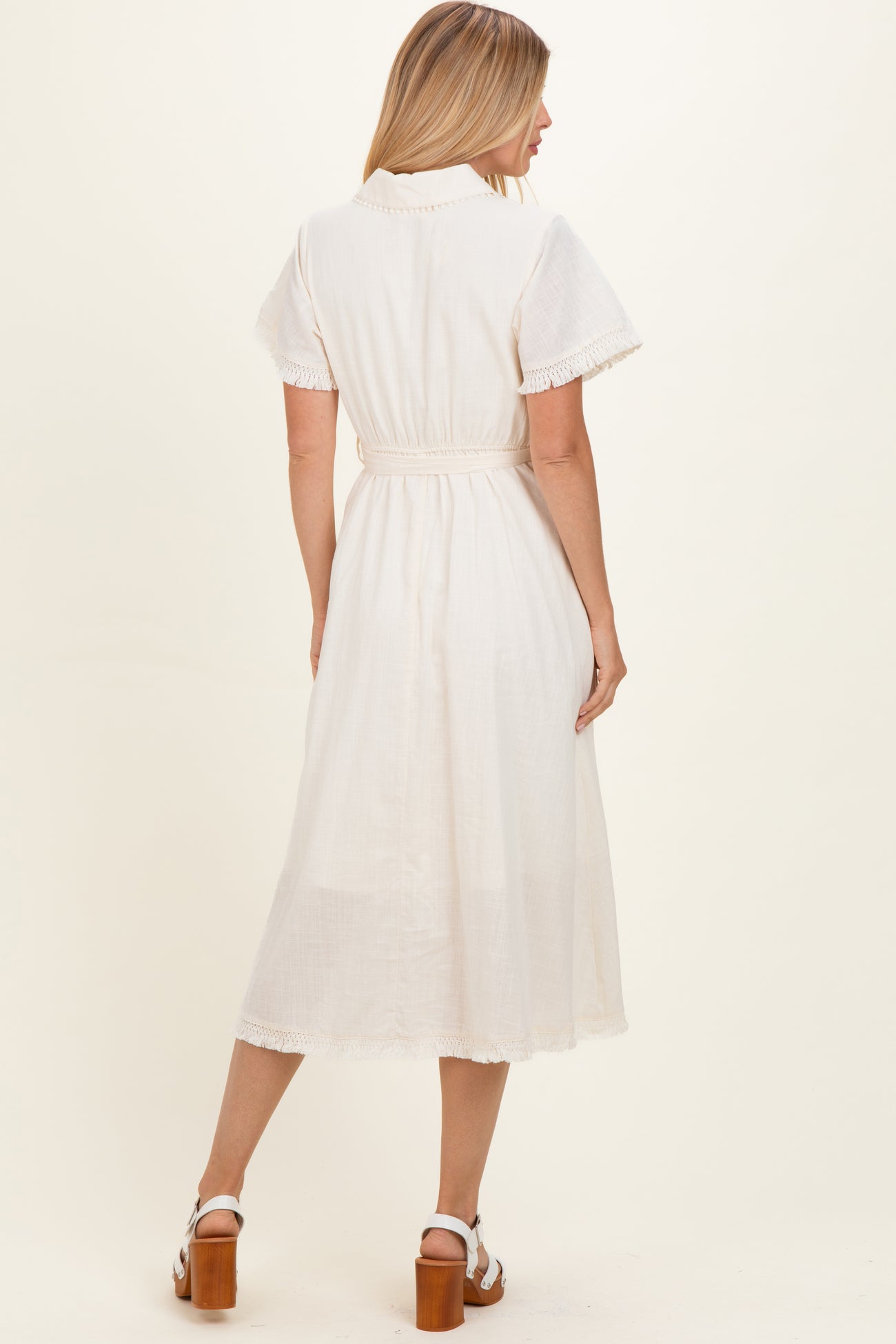 woman wearing a white midi dress with short sleeves and a belted waist, shown from the back