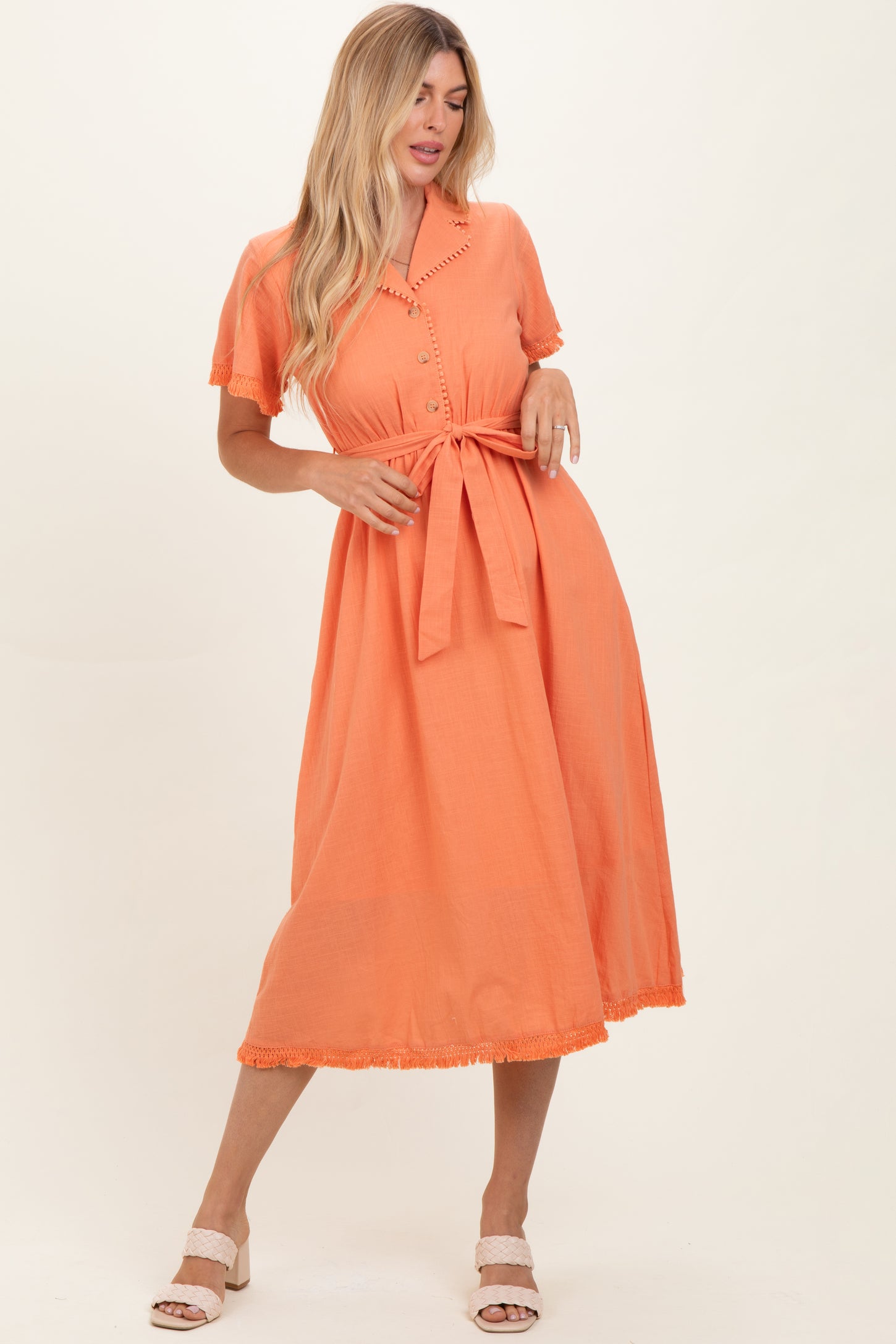 woman wearing an orange button-up midi dress with a tie waist and short sleeves, featuring lace trim