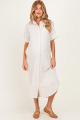 woman wearing a light beige short sleeve maternity dress with a button front and a relaxed fit