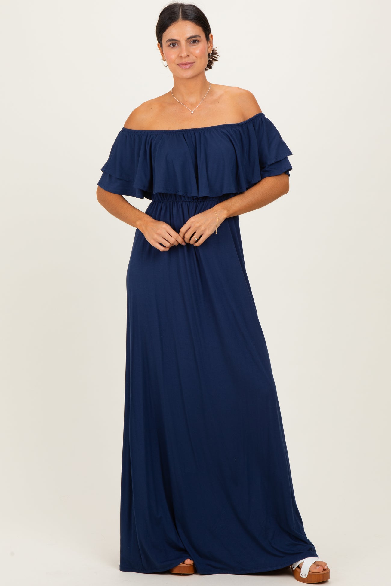 woman wearing a navy blue off-the-shoulder maxi dress with ruffled sleeves and a cinched waist