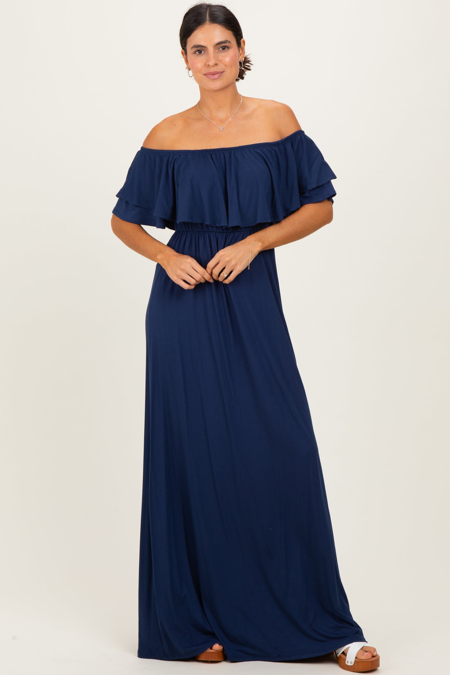 woman wearing a navy blue off-the-shoulder maxi dress with ruffled sleeves and a cinched waist