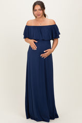 woman wearing a navy off-shoulder maternity dress with ruffle details and holding her baby bump