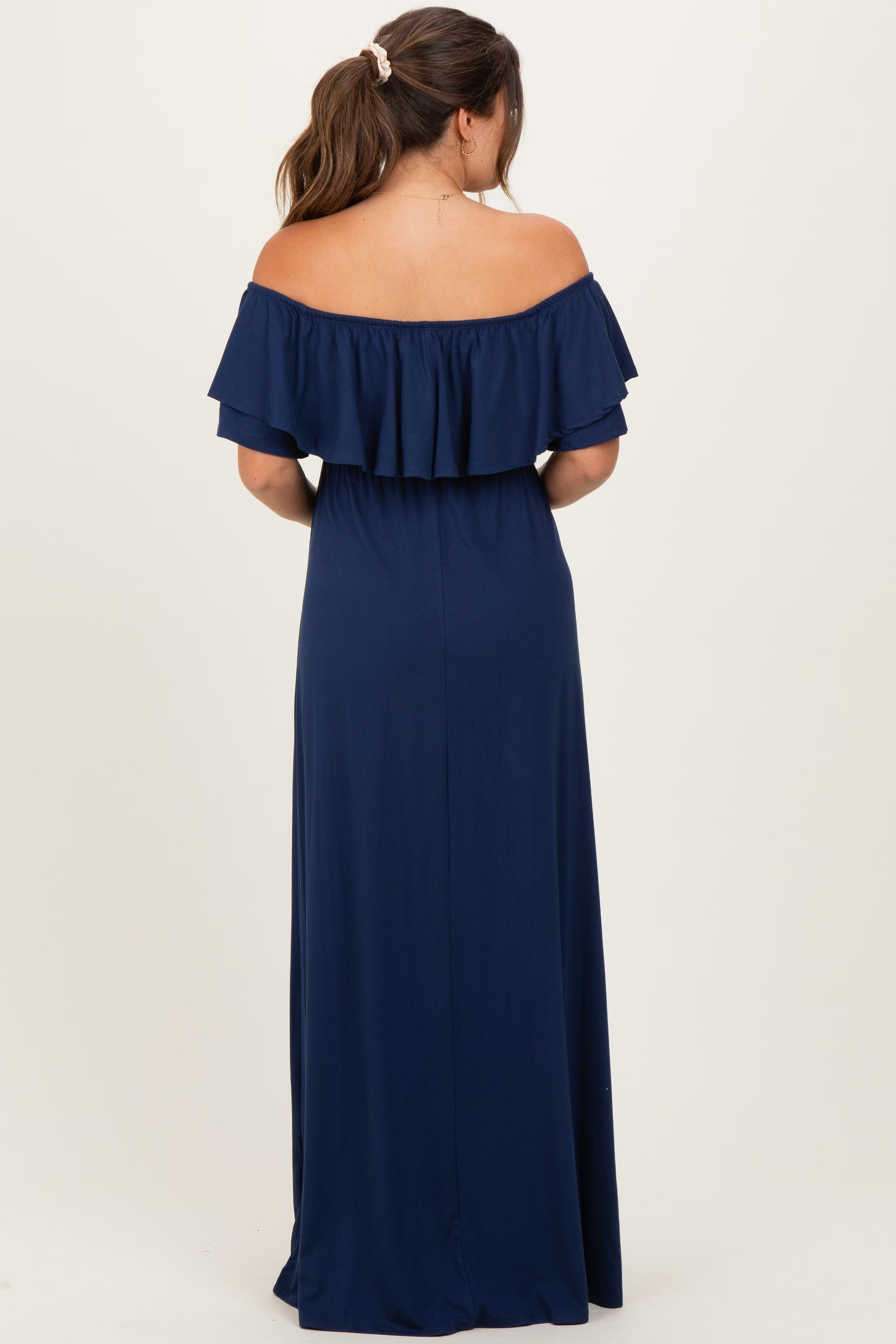 woman wearing a navy blue off-the-shoulder maternity dress with ruffle details, showing her back