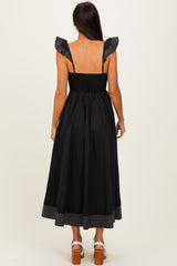 woman wearing a black midi dress with ruffled straps and striped hem, shown from the back