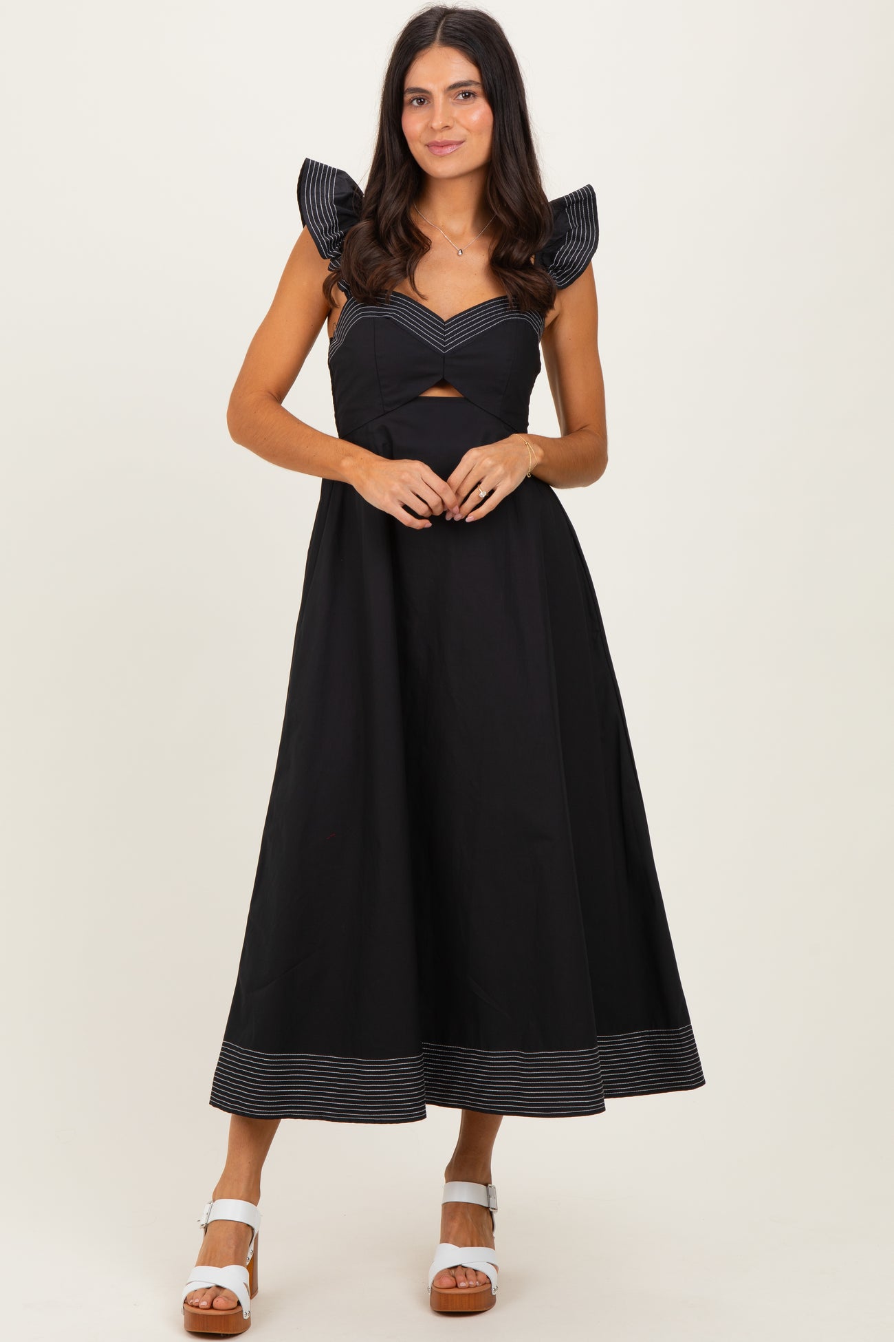 woman wearing a black maxi dress with striped puff sleeves and a cutout detail at the waist